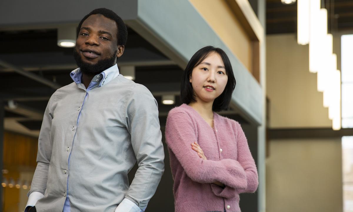 Photo of a college-aged woman standing next to a college-aged man both looking at the camera smiling. 